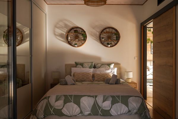 Schlafzimmer mit 160-cm-Bett, Rattanregalen und Ankleide mit Schiebetüren