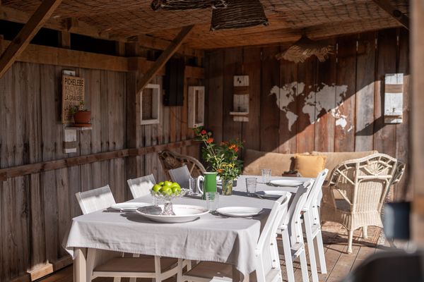 Gedeckter Tisch unter dem Holzdach der Sommerküche